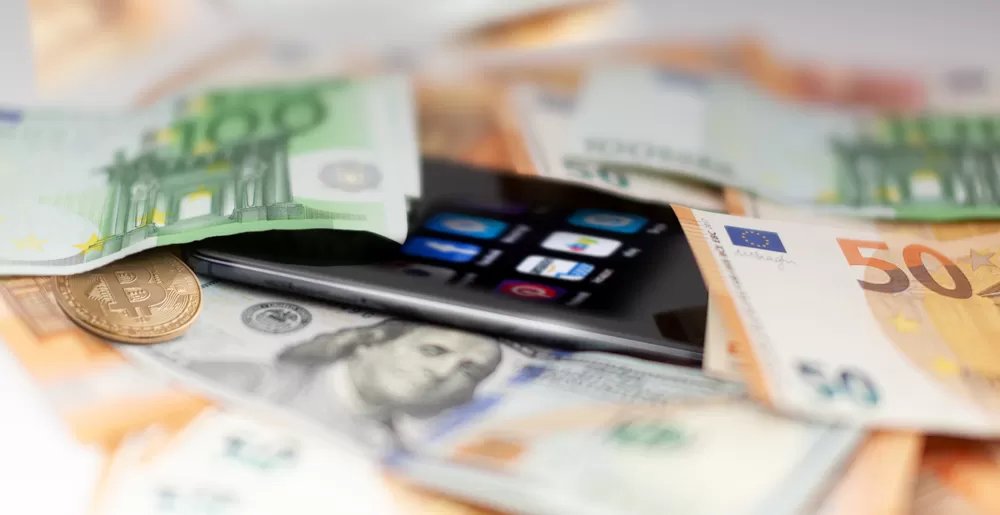 A mobile phone is sitting on a pile of money, symbolizing the relief offered by Merchant Cash Advance.